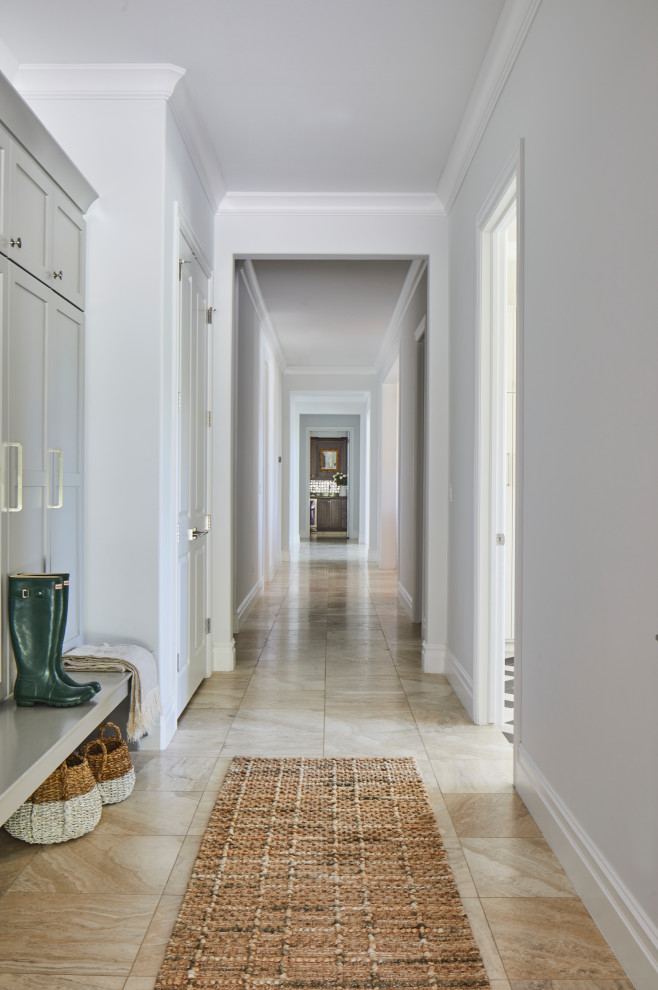 Свежая идея для дизайна: огромный коридор в стиле неоклассика (современная классика) с белыми стенами, полом из травертина и бежевым полом - отличное фото интерьера