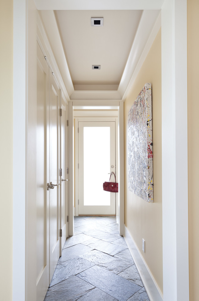 На фото: коридор среднего размера в стиле неоклассика (современная классика) с желтыми стенами и полом из сланца с