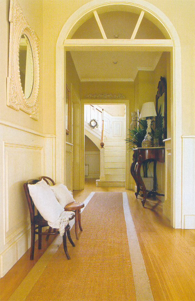 На фото: огромный коридор в классическом стиле с белыми стенами и паркетным полом среднего тона с