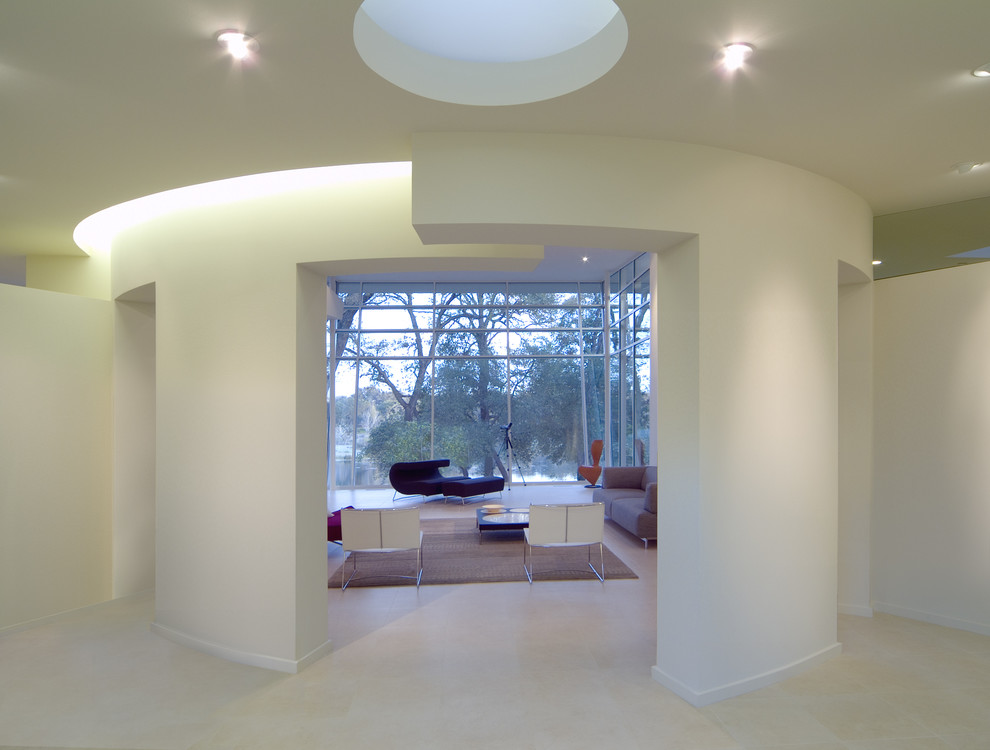 Пример оригинального дизайна: большой коридор в стиле модернизм с белыми стенами и полом из известняка