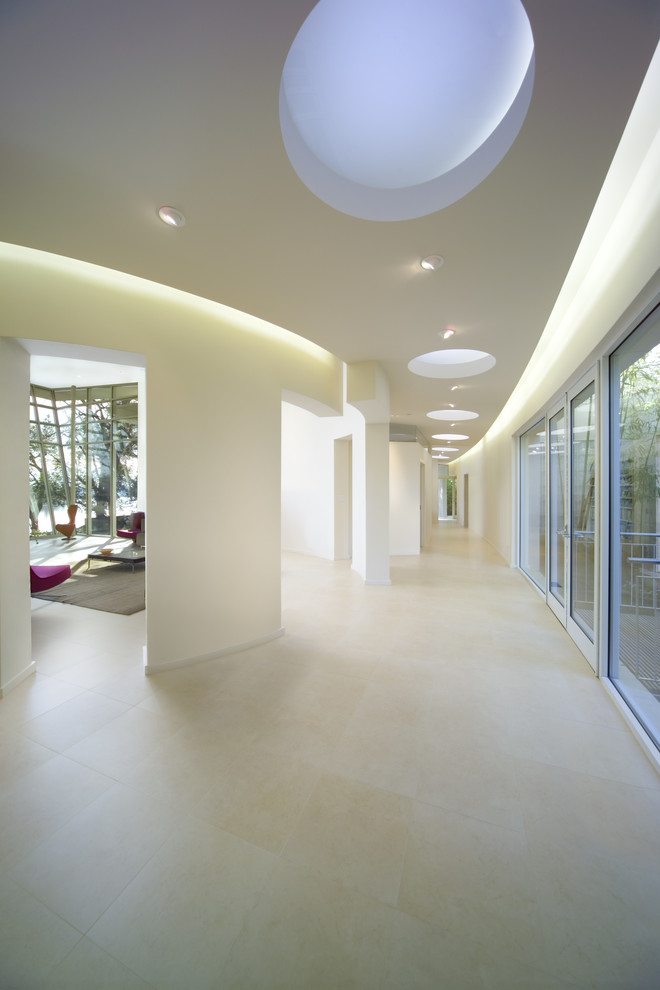 Ejemplo de recibidores y pasillos minimalistas grandes con paredes blancas y suelo de piedra caliza