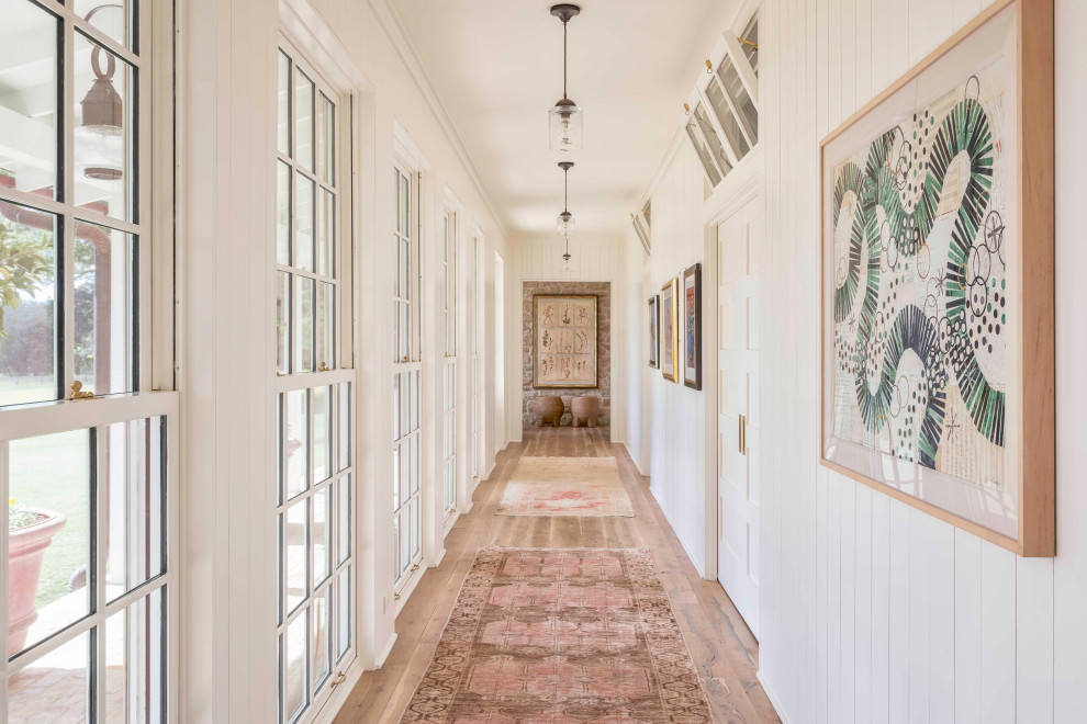 Immagine di un ingresso o corridoio country con pareti bianche, pavimento in legno massello medio, pavimento marrone e pareti in perlinato