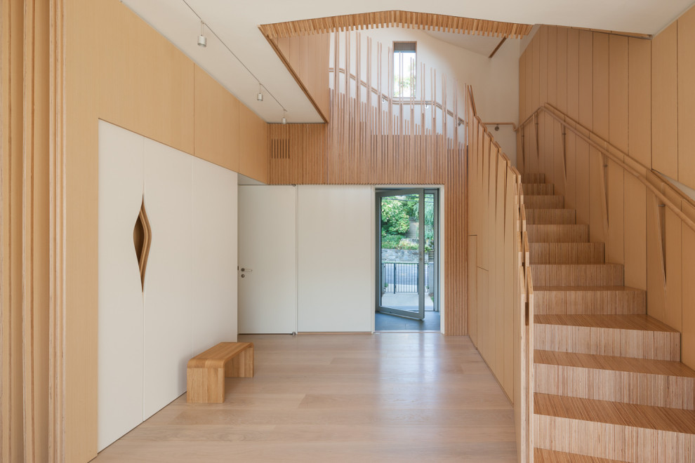 Immagine di un ingresso o corridoio moderno con pareti beige, parquet chiaro, pavimento beige e pareti in legno