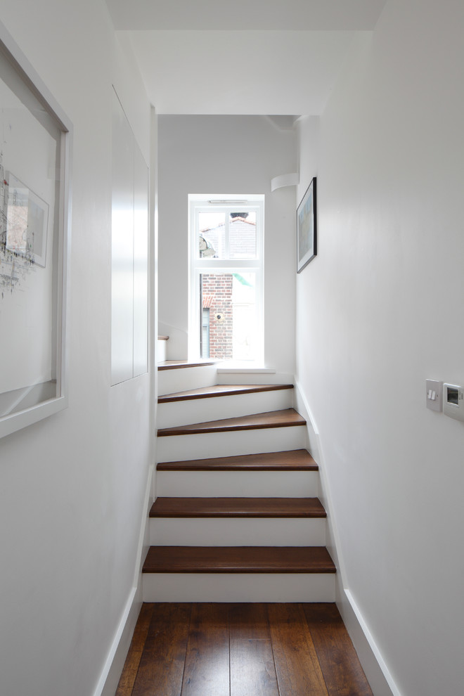 Exempel på en liten modern hall, med vita väggar, mörkt trägolv och brunt golv
