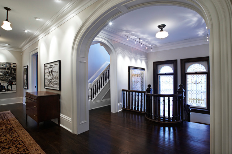 Пример оригинального дизайна: большой коридор в стиле неоклассика (современная классика) с белыми стенами, темным паркетным полом и коричневым полом