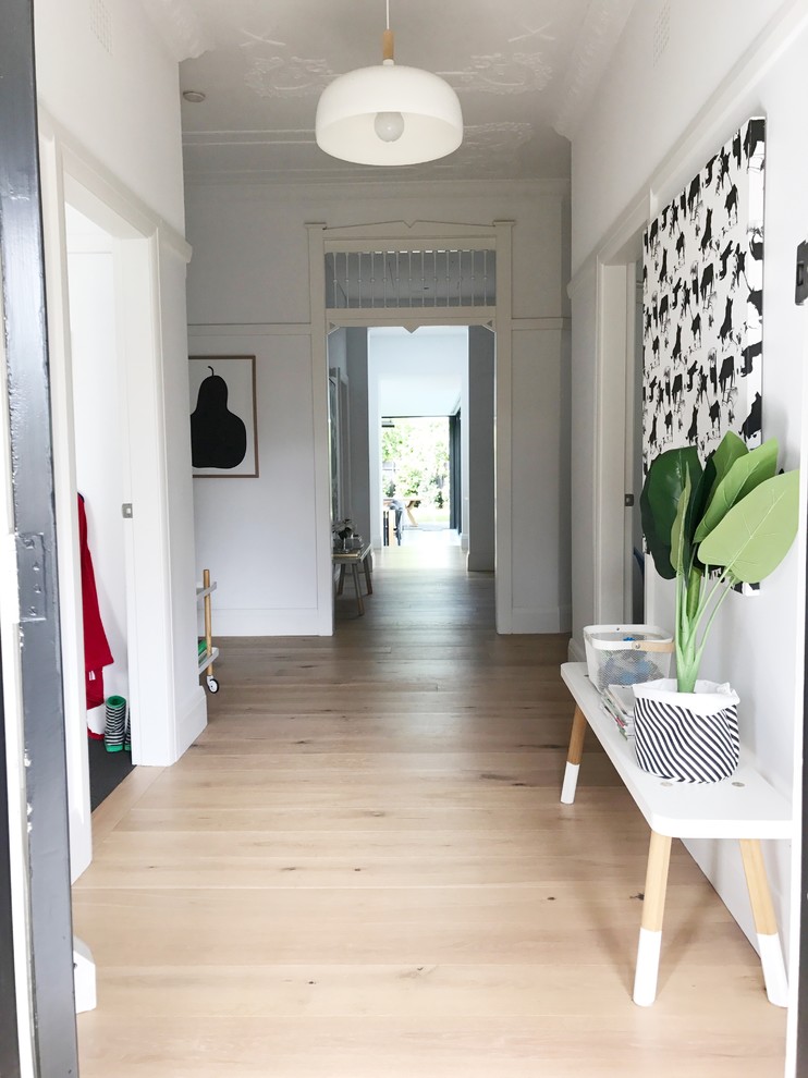 Foto de recibidores y pasillos nórdicos grandes con paredes blancas, suelo de madera clara y suelo beige