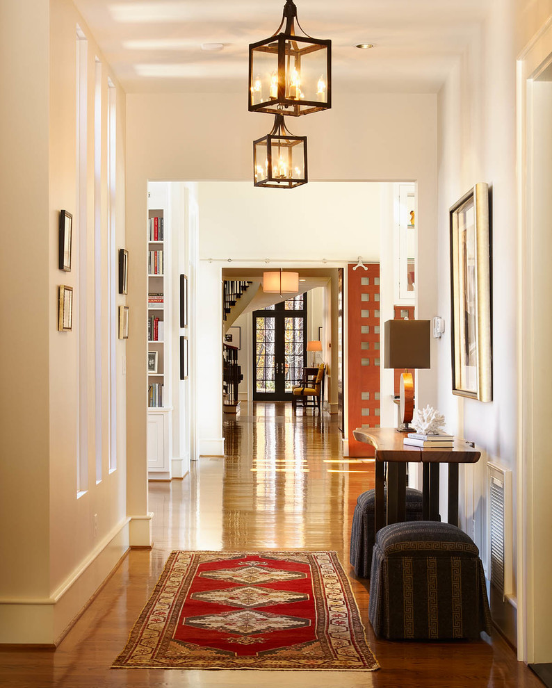 Cette image montre un très grand couloir traditionnel avec un sol en bois brun et un mur blanc.