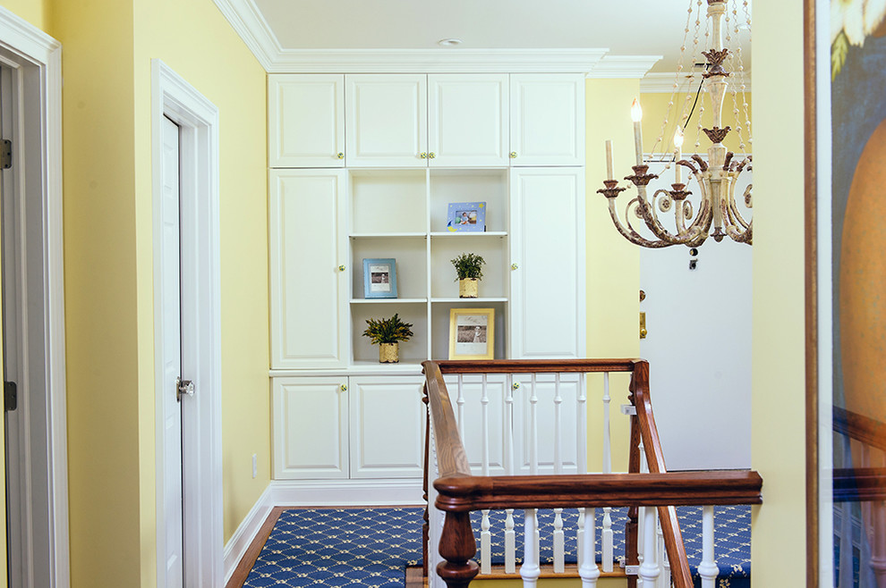 На фото: коридор среднего размера в стиле неоклассика (современная классика) с желтыми стенами, ковровым покрытием и коричневым полом