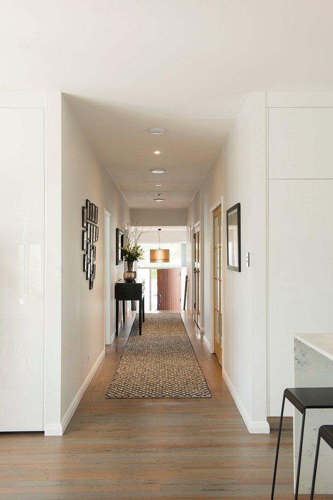 Idées déco pour un grand couloir contemporain avec un mur blanc, un sol en bois brun et un sol marron.