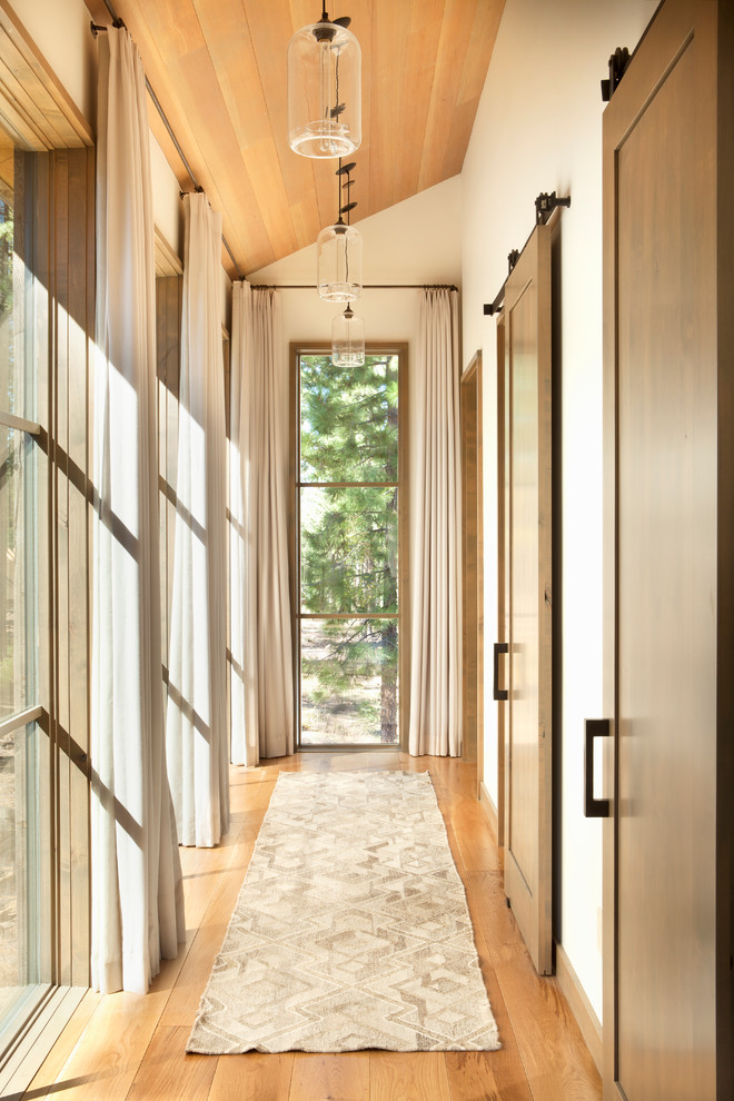 Example of a mid-sized mountain style light wood floor hallway design in Sacramento with white walls
