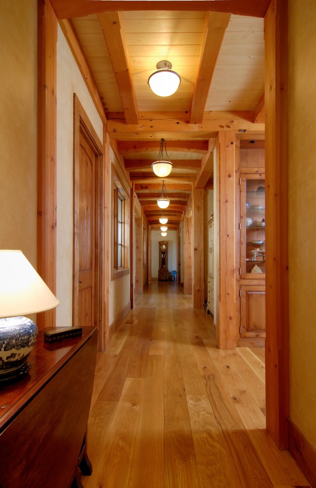 Ejemplo de recibidores y pasillos rurales grandes con paredes beige, suelo de madera clara y iluminación