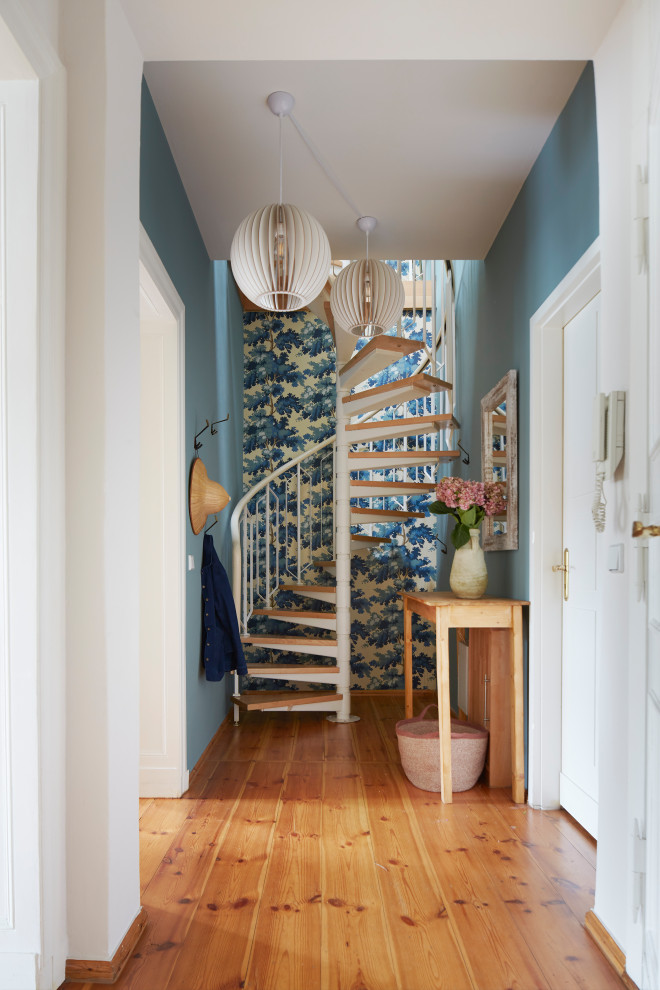 Cette photo montre un couloir éclectique avec un mur bleu, un sol en bois brun, un sol marron et du papier peint.