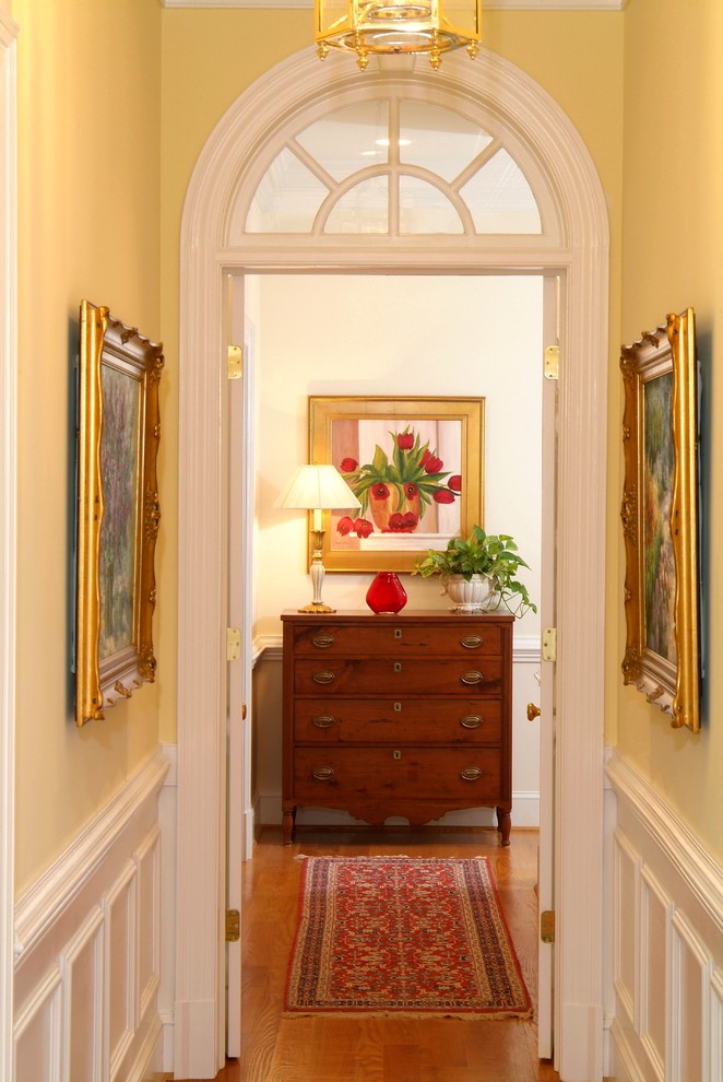 Mid-sized elegant medium tone wood floor hallway photo in Richmond with yellow walls