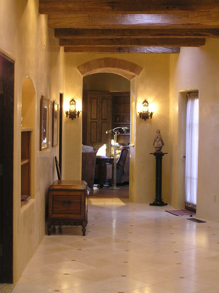 На фото: огромный коридор в классическом стиле с желтыми стенами и полом из травертина с
