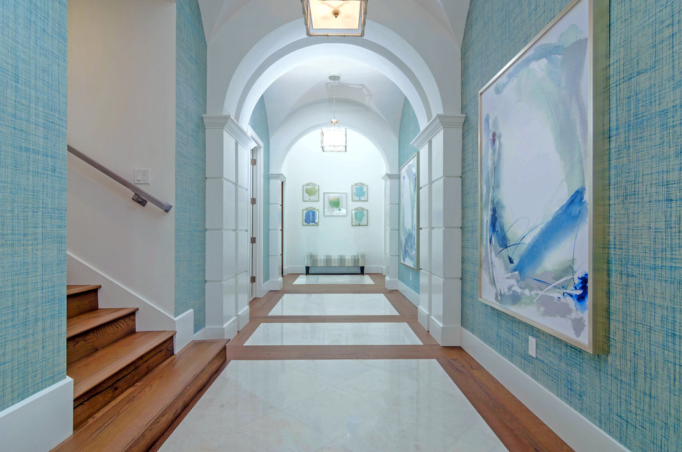 Стильный дизайн: огромный коридор в стиле неоклассика (современная классика) с синими стенами и мраморным полом - последний тренд
