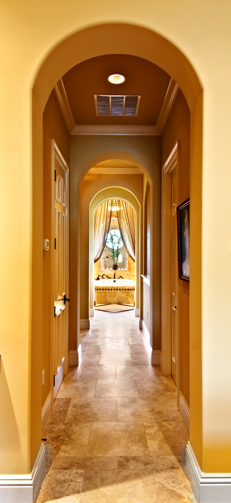 Пример оригинального дизайна: большой коридор в средиземноморском стиле с желтыми стенами и полом из травертина