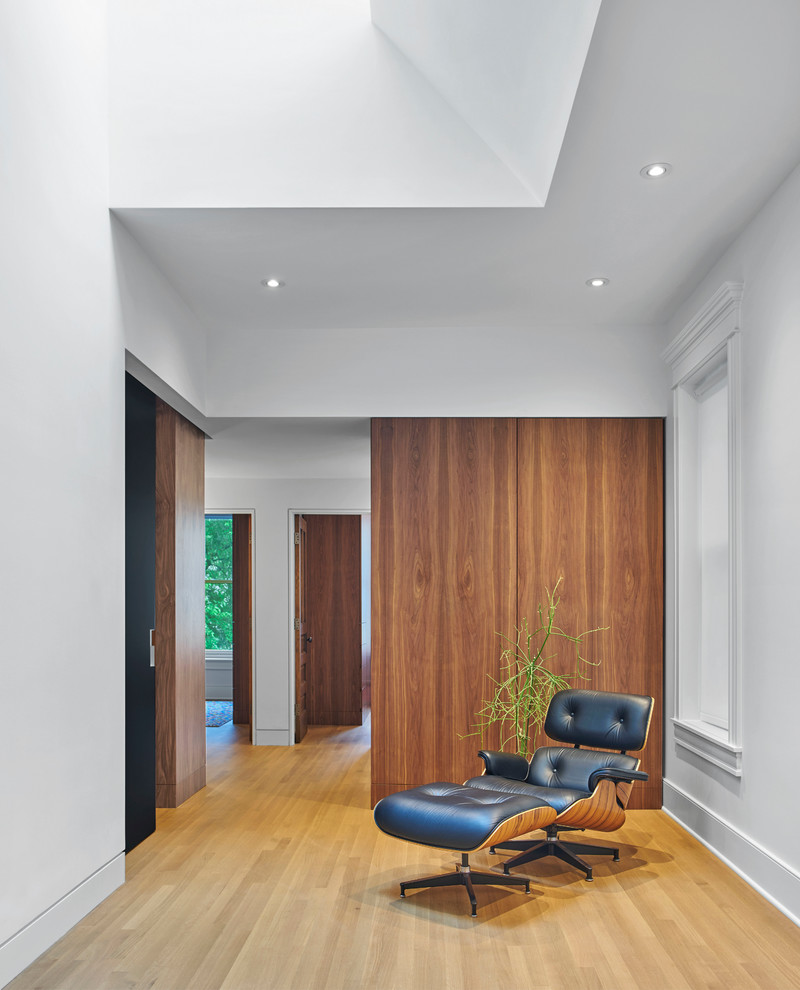 Esempio di un ingresso o corridoio minimalista con pareti bianche, parquet chiaro e pavimento marrone