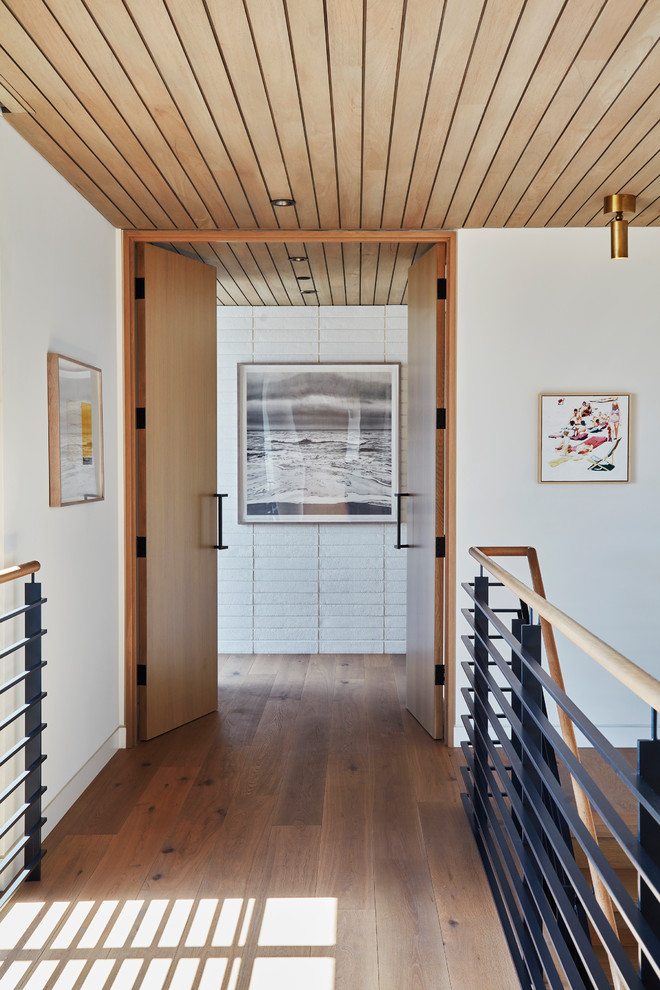 Ispirazione per un ingresso o corridoio contemporaneo con pareti bianche, pavimento in legno massello medio e pavimento marrone