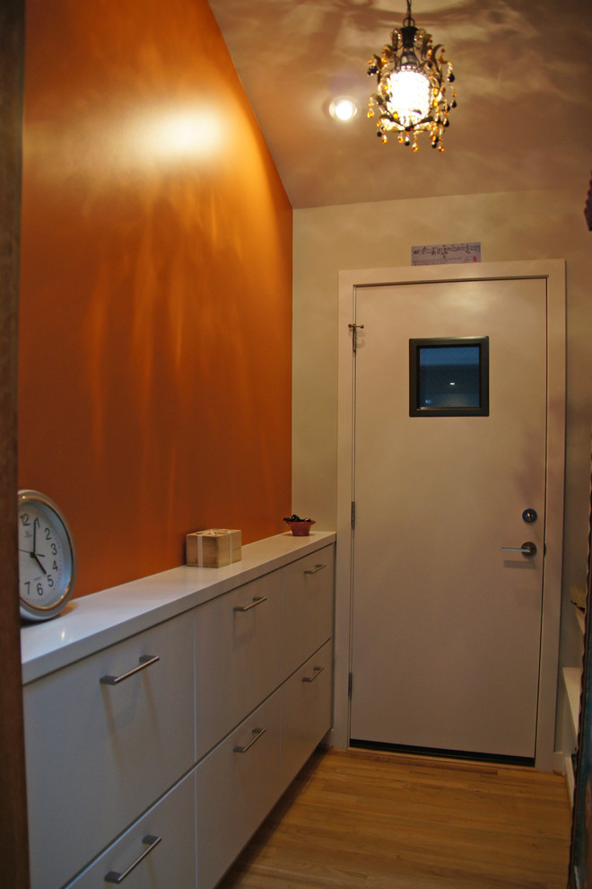 Foto på en mellanstor funkis hall, med orange väggar, ljust trägolv och brunt golv