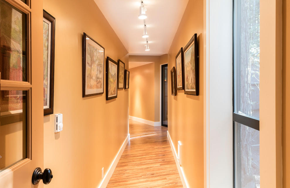 Hallway - large transitional medium tone wood floor and orange floor hallway idea in San Francisco with orange walls