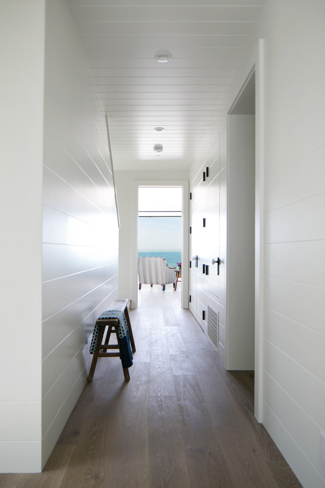 На фото: коридор среднего размера в морском стиле с белыми стенами и коричневым полом