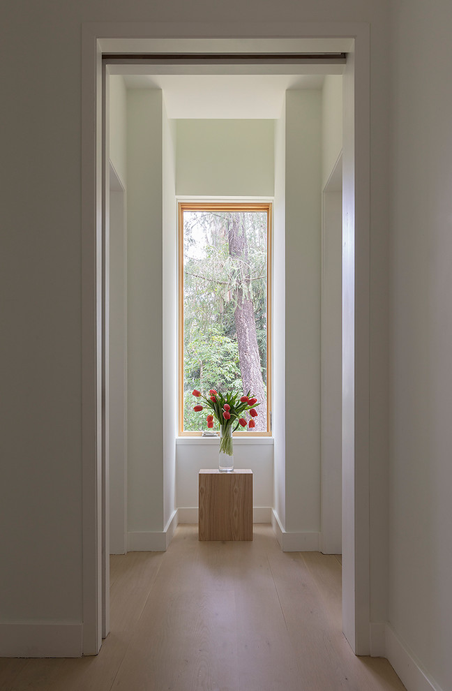 Réalisation d'un couloir minimaliste de taille moyenne avec un mur blanc, parquet clair et un sol beige.