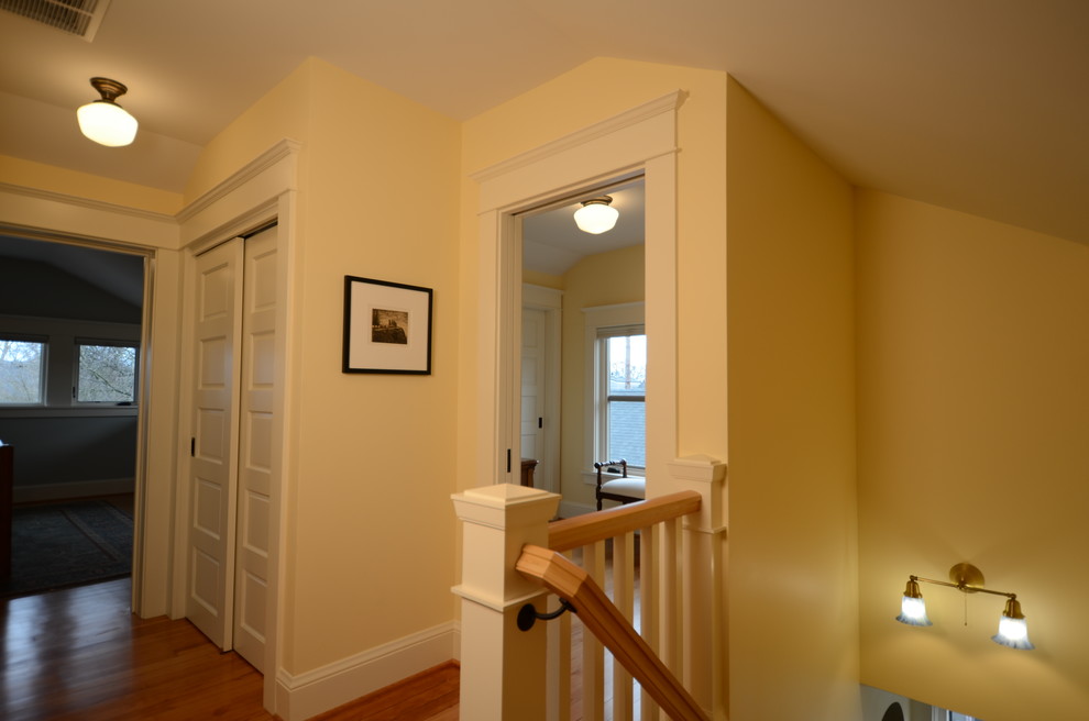 Idée de décoration pour un couloir craftsman de taille moyenne avec un mur jaune et parquet clair.