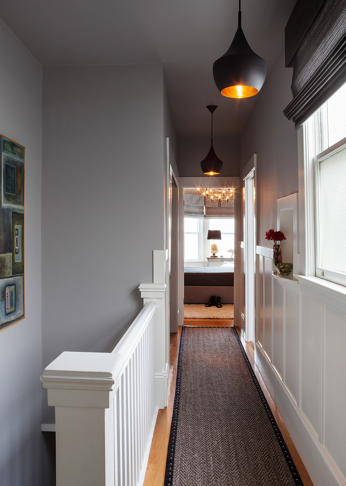 Cette photo montre un petit couloir moderne avec un mur gris et un sol en bois brun.