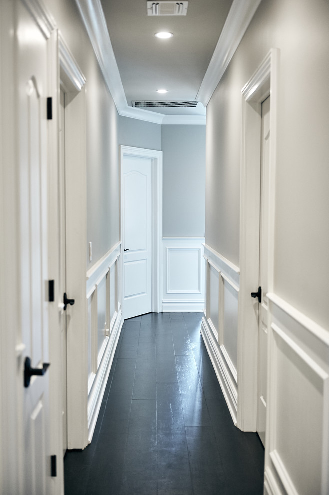 На фото: большой коридор в стиле неоклассика (современная классика) с серыми стенами, темным паркетным полом и черным полом с