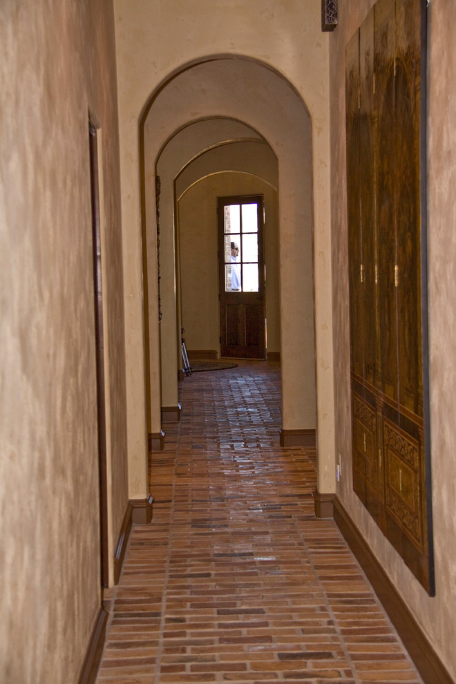 オースティンにある中くらいな地中海スタイルのおしゃれな廊下 (ベージュの壁、レンガの床) の写真