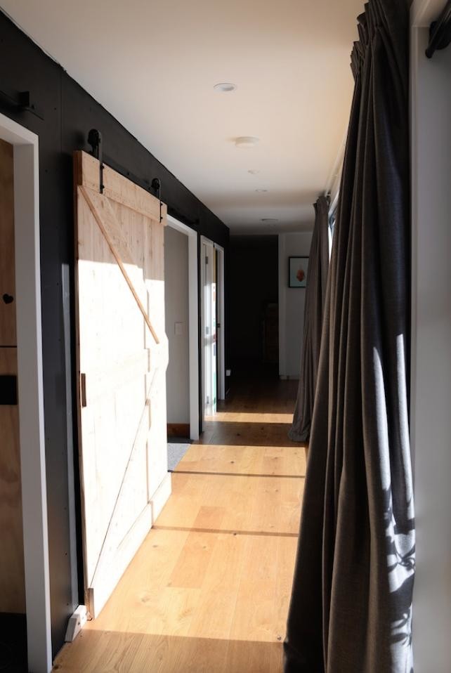 Idee per un grande ingresso o corridoio moderno con pareti nere, parquet chiaro e pavimento beige