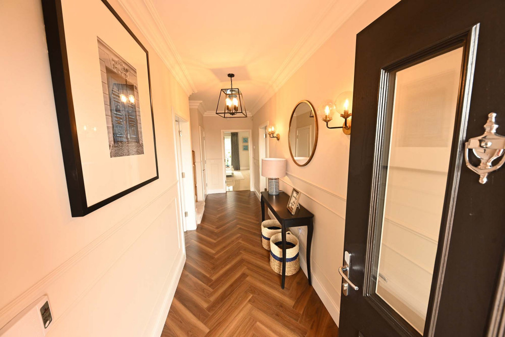 Cette photo montre un couloir éclectique avec un mur blanc, sol en stratifié et un sol marron.