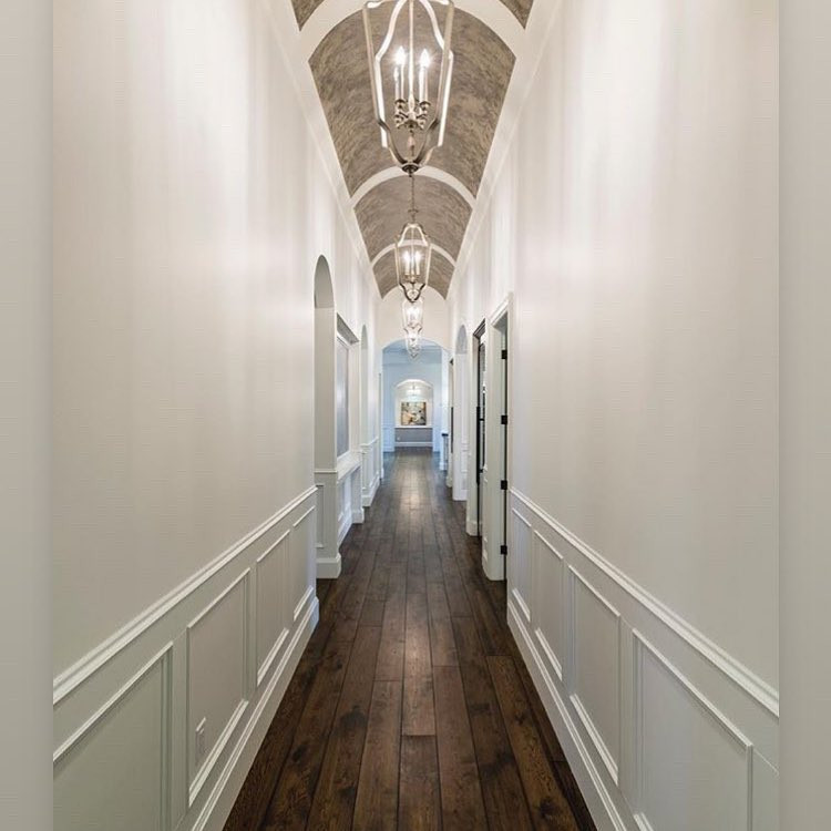Cette image montre un couloir design de taille moyenne avec un mur blanc, parquet foncé, un sol marron et du lambris.