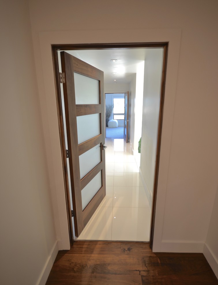 Ispirazione per un ingresso o corridoio design con pareti bianche, pavimento in legno massello medio e pavimento marrone