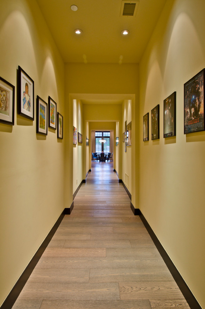 Idee per un grande ingresso o corridoio mediterraneo con pareti gialle e pavimento in legno massello medio