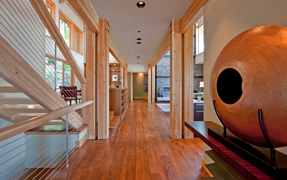 Cette image montre un grand couloir design avec un mur beige et un sol en bois brun.