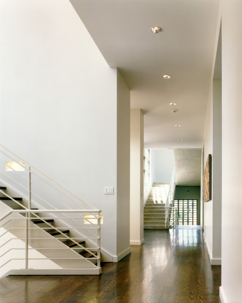 Exemple d'un couloir moderne avec un mur blanc et parquet foncé.