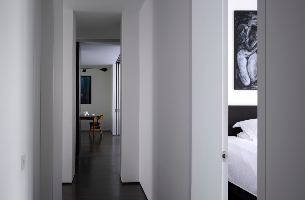 Стильный дизайн: коридор в современном стиле с белыми стенами и темным паркетным полом - последний тренд