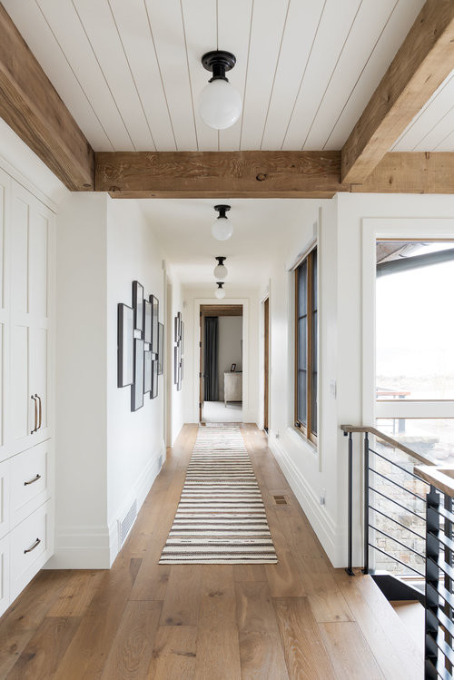 Aménagement d'un grand couloir classique avec un mur blanc, un sol en bois brun et un sol marron.