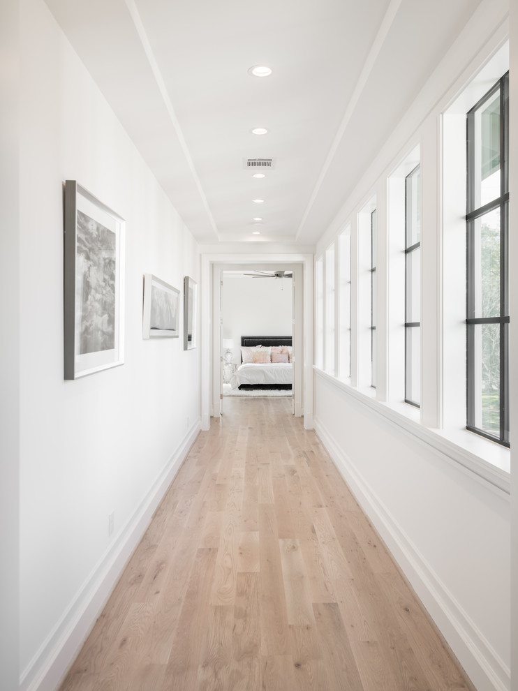 Exempel på en mellanstor klassisk hall, med vita väggar, ljust trägolv och beiget golv