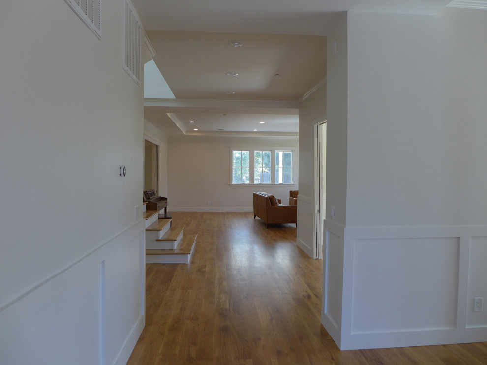 Immagine di un ampio ingresso o corridoio country con pareti bianche, parquet chiaro, pavimento marrone, soffitto ribassato e pannellatura