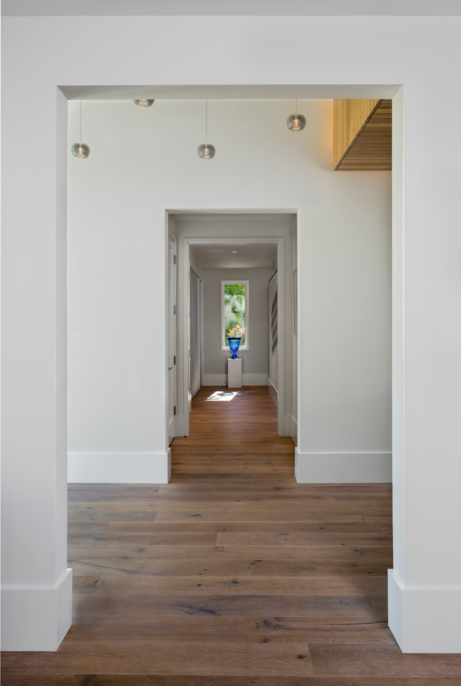 Ispirazione per un ingresso o corridoio minimal di medie dimensioni con pareti bianche, parquet chiaro e pavimento beige