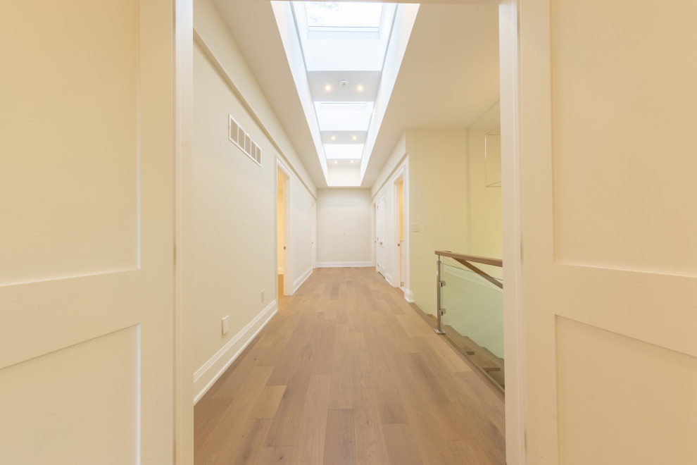 Exemple d'un grand couloir tendance avec un mur blanc, parquet clair et un sol beige.