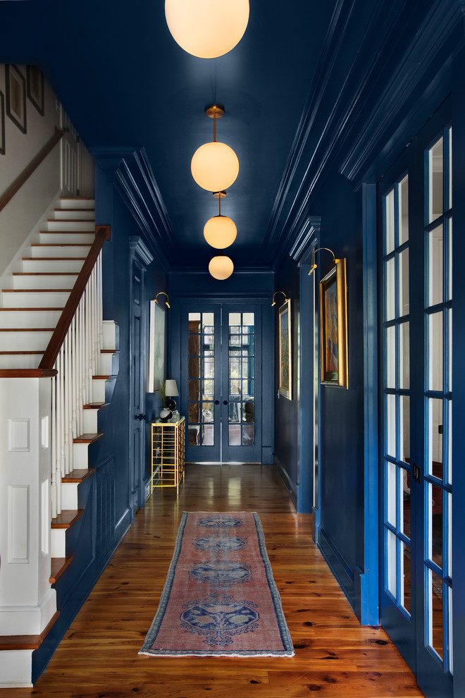 Idée de décoration pour un grand couloir tradition avec un mur bleu, un sol en bois brun et un sol marron.