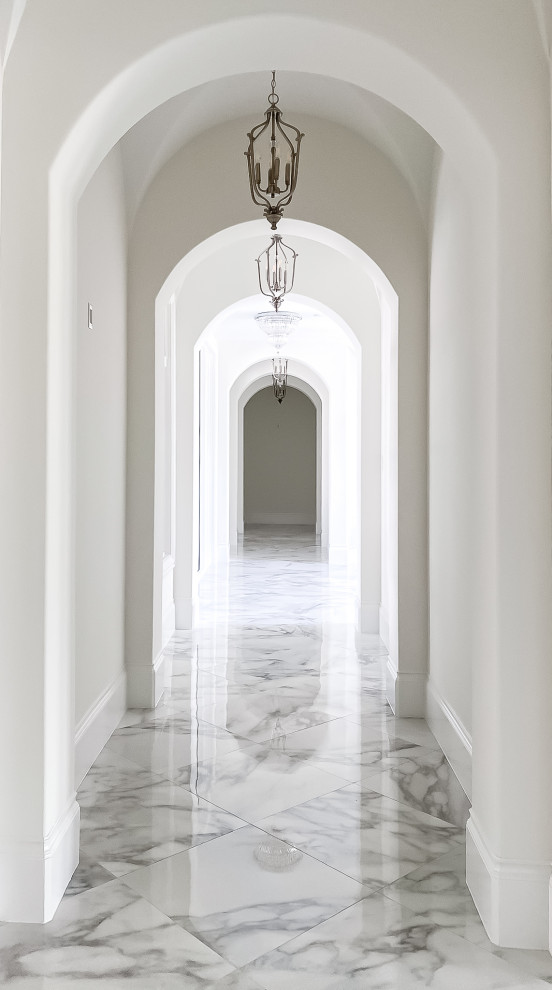 Idée de décoration pour un grand couloir tradition avec un mur blanc, un sol en carrelage de porcelaine, un sol gris et un plafond voûté.