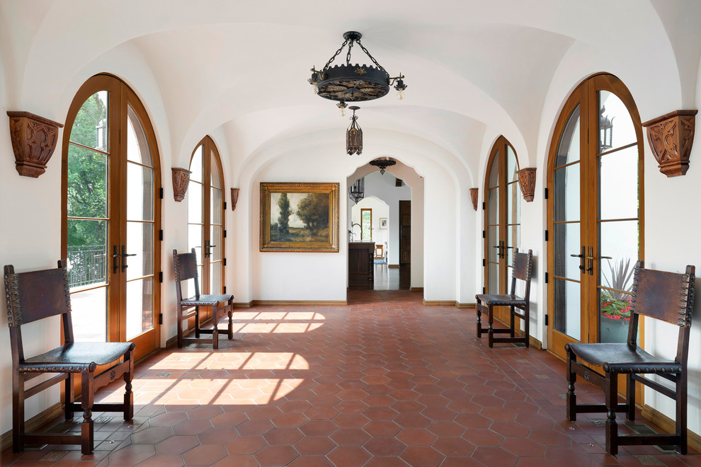 Immagine di un ampio ingresso o corridoio mediterraneo con pareti bianche, pavimento in terracotta e pavimento marrone