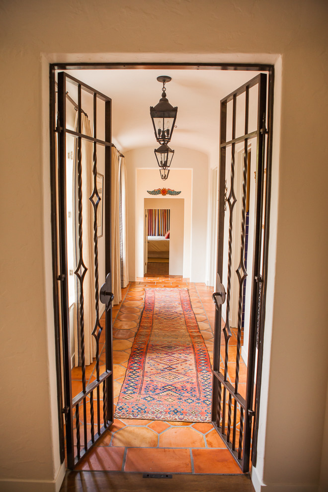 Inspiration for a mid-sized mediterranean terra-cotta tile and orange floor hallway remodel in Los Angeles with beige walls