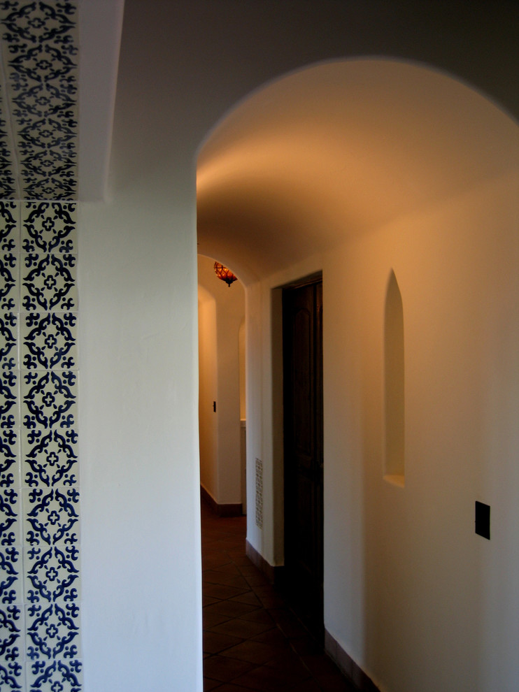 Inspiration pour un couloir méditerranéen de taille moyenne avec un mur blanc, tomettes au sol et un sol rouge.
