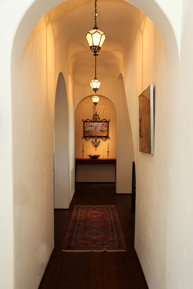 Cette image montre un couloir traditionnel avec un mur blanc et parquet foncé.