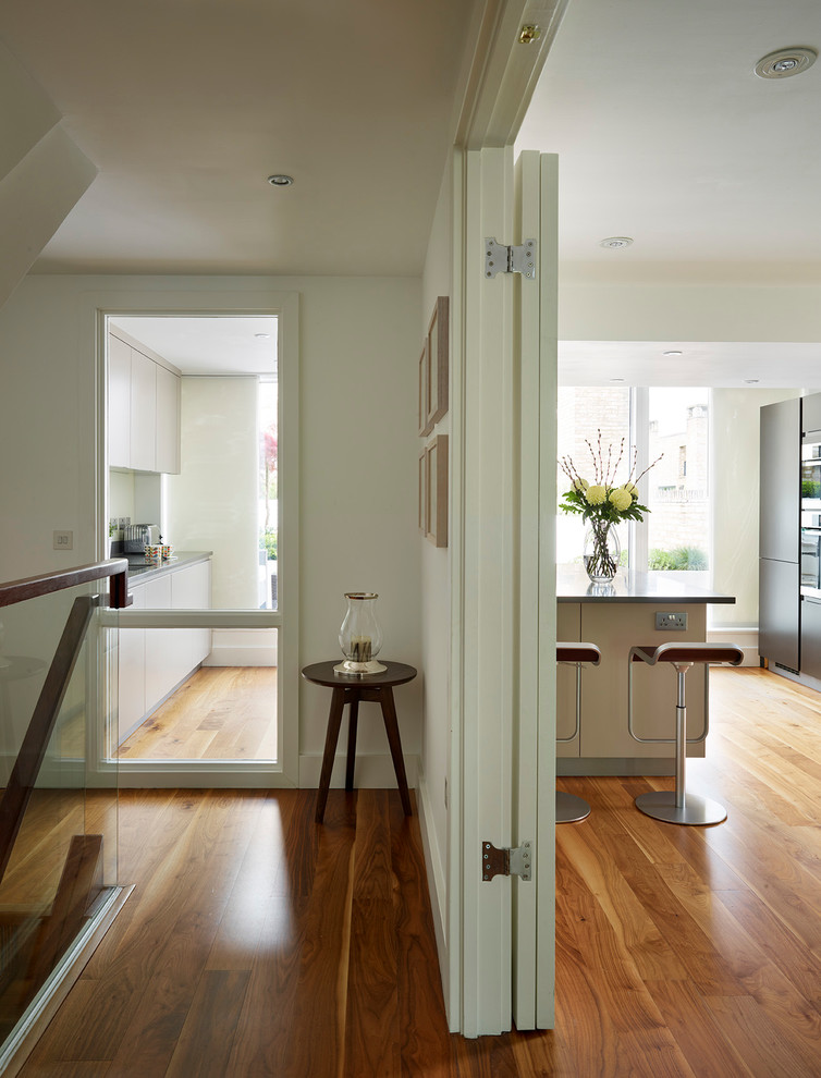 Cette image montre un couloir design avec un mur blanc et un sol en bois brun.